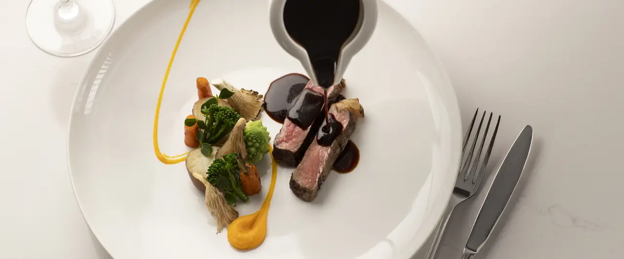 Ein saftiges Steak mit Soße, serviert mit einem Glas Rotwein.