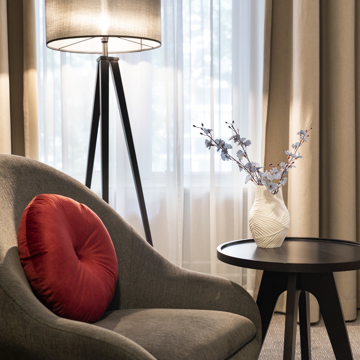 Een stoel op een hotelkamer naast een tafel en lamp