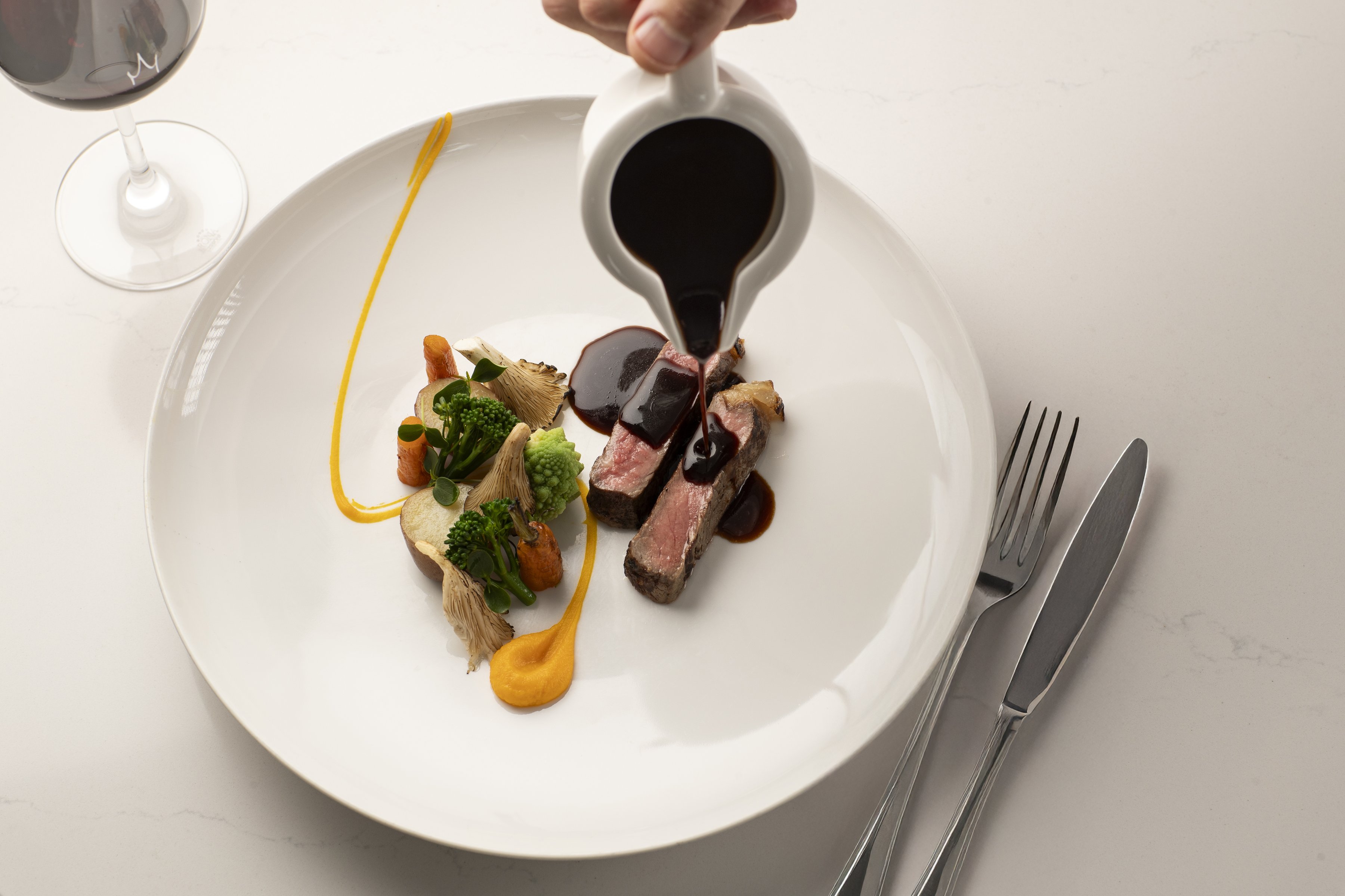 A juicy steak topped with gravy, served with a glass of red wine.