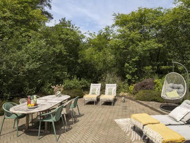 Luxuriöser Spa-Garten mit Lounge-Sets, Hängestuhl und Esstisch umgeben von üppigem Grün im Clarins Spa Wellness Centre.