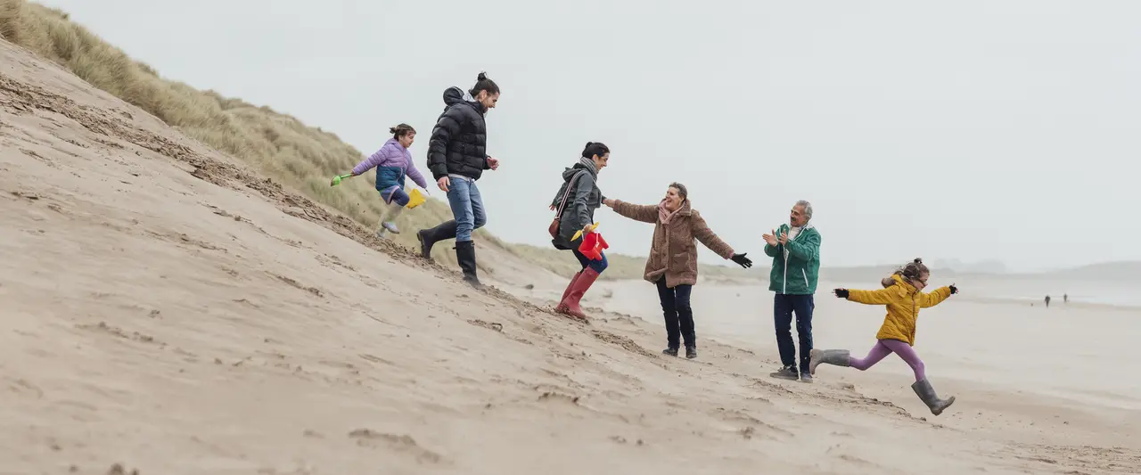 Een familie dat samen aan het uitwaaien is op het strand.