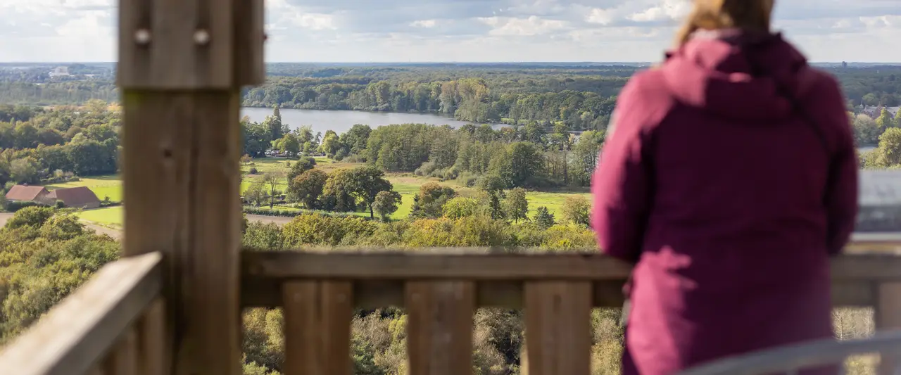 Vrouw kijkt uit over een rivierlandschap in Limburg