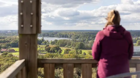 Vrouw kijkt uit over een rivierlandschap in Limburg