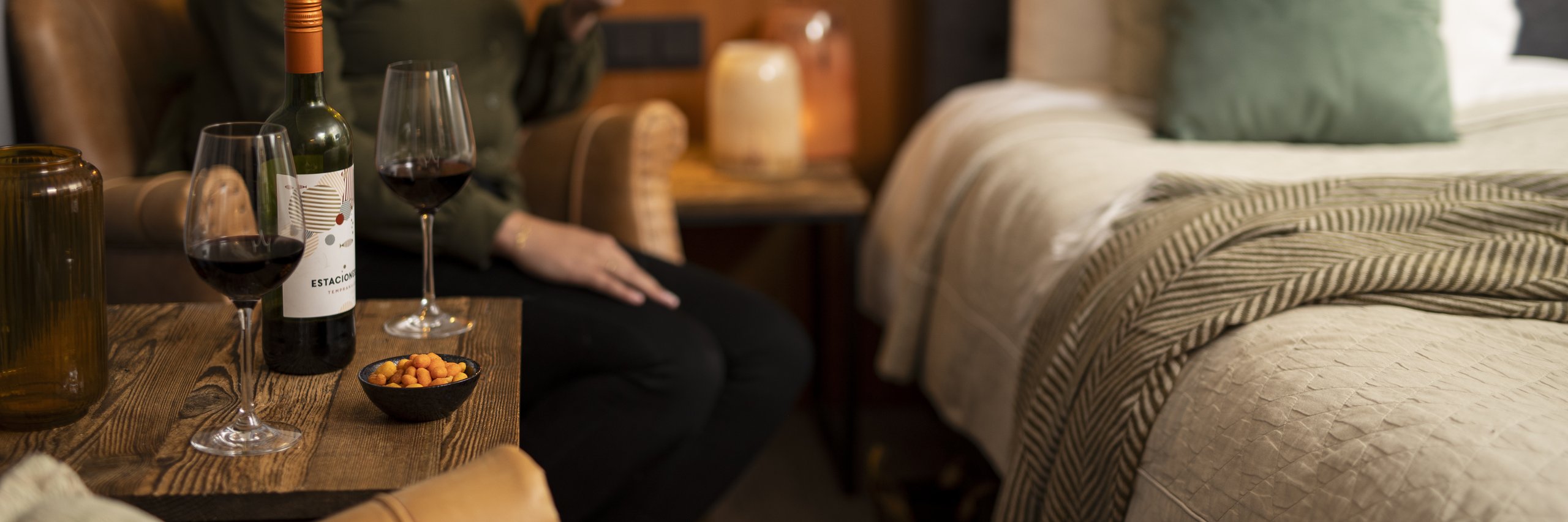 Een vrouw in een hotelkamer met haar e-reader en rode wijn.