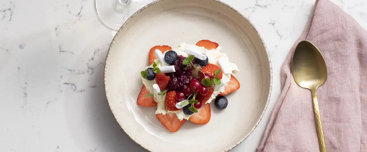Dessert mit Erdbeeren auf einem schönen Teller mit Heidelbeeren und roten Früchten
