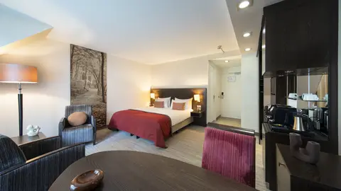 Executive room met zithoek, koffiezetapparaat en uitzicht op het bos bij Hotel De Bovenste Molen.
