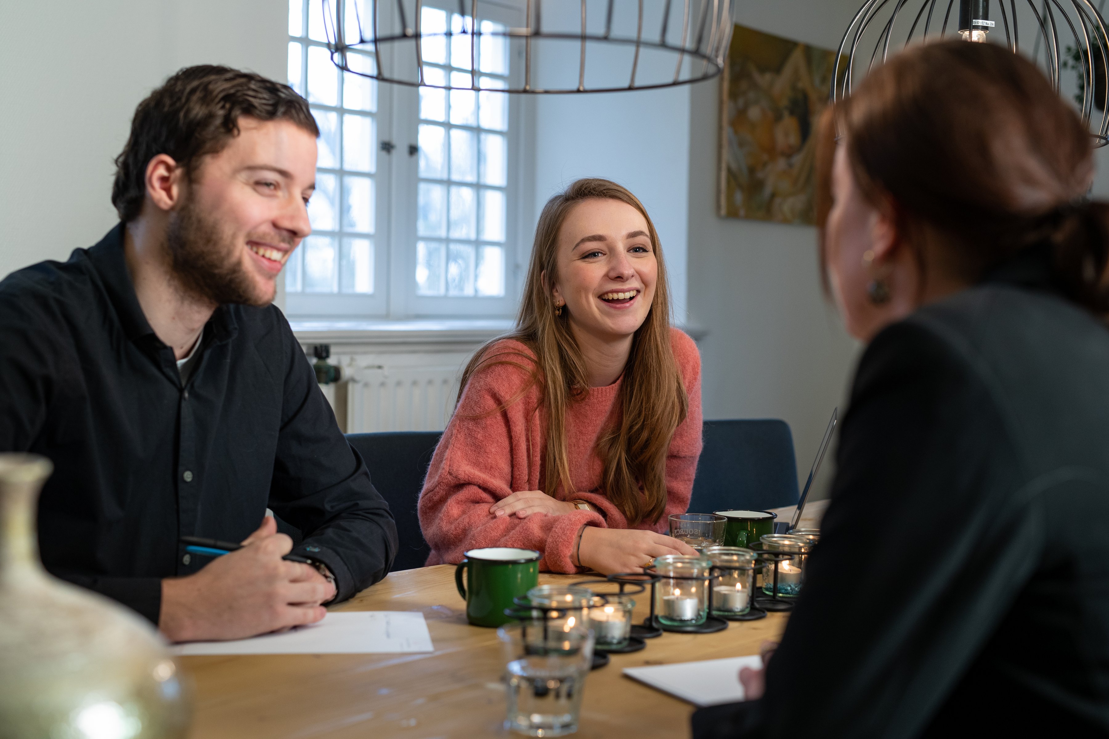 Three smiling people at the meeting table