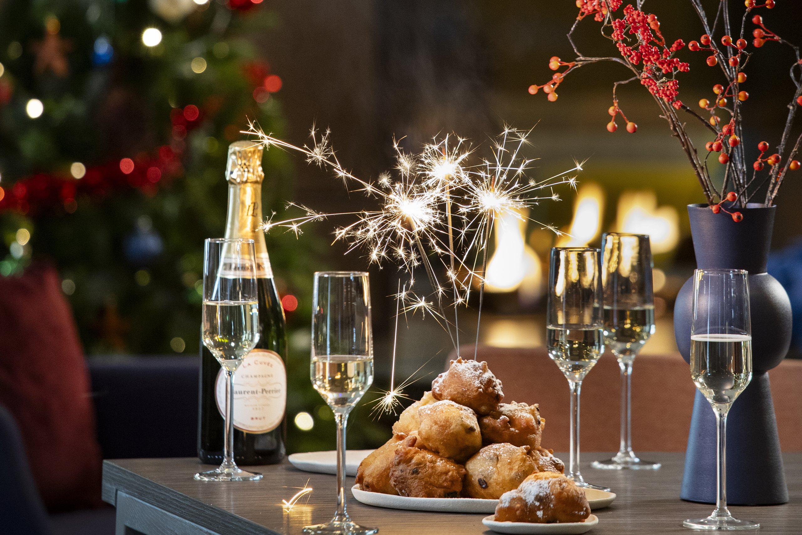 Een gedekte tafel met champagne en oliebollen.