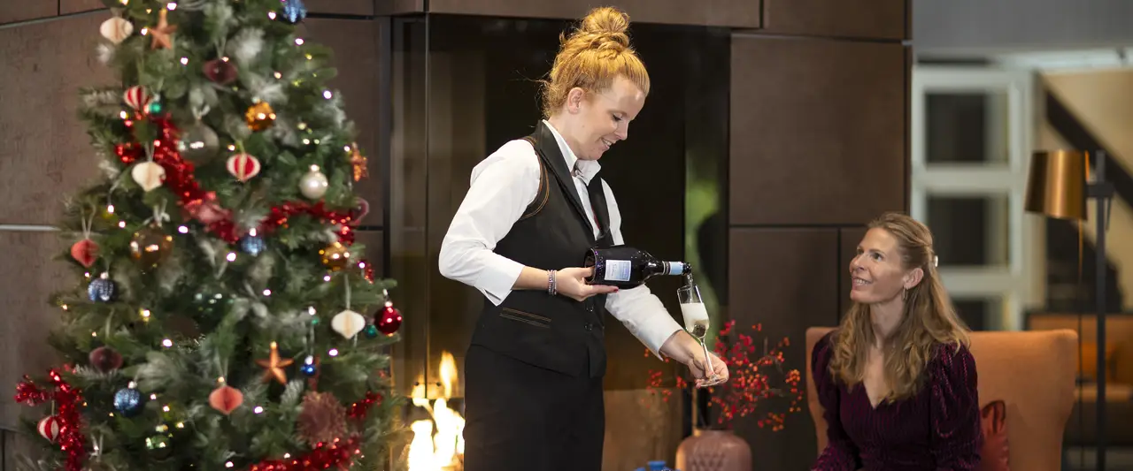 Bilderberg medewerkster die een glas champagne inschenkt voor een gast.