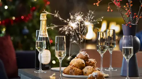 Een gedekte tafel met champagne en oliebollen.
