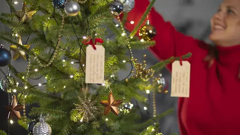 Een vrouw die vrolijk de kerstboom optuigt.
